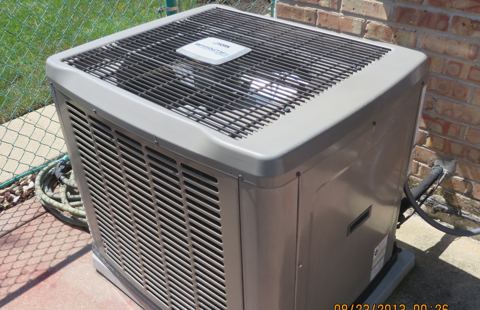 Central air conditioner condenser beside a house