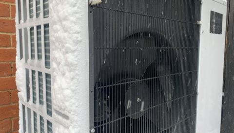 Heat pump outdoor unit covered in snow and frost