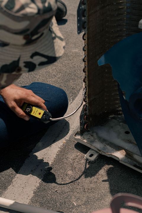 Technician testing a mini split outdoor unit with copper lines and grounding requirements for mini splits visible