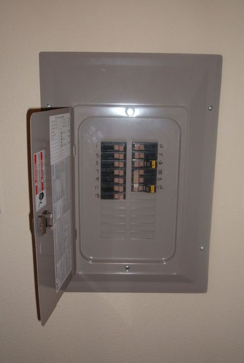 Open electrical panel with numbered circuit breakers, relevant for determining mini split wire size requirements