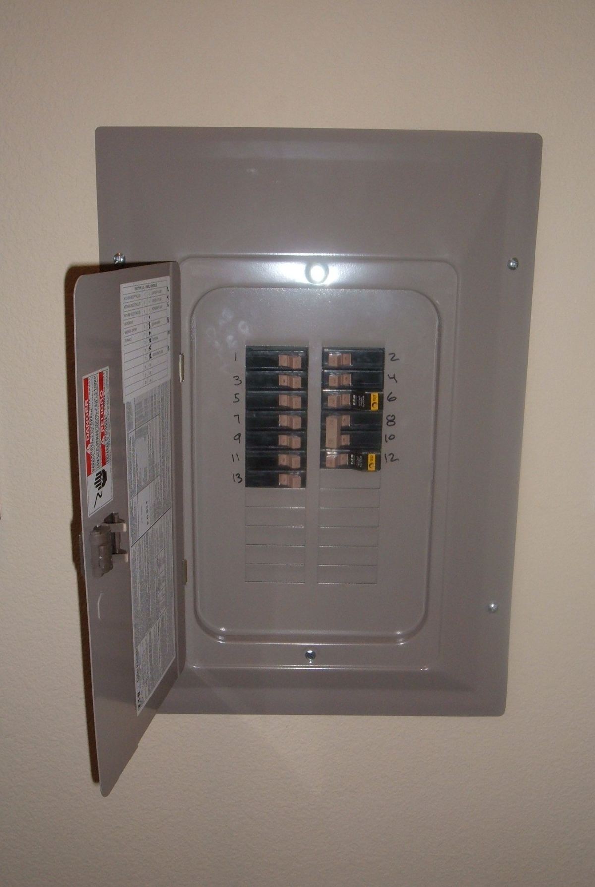 Open electrical panel with numbered circuit breakers, relevant for determining mini split wire size requirements